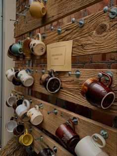 Cups hanging on hooks on driftwood against a brick wall at a coffee shop. Thrifted Mugs, Mug Wall, Mobile Coffee Shop, Opening A Coffee Shop, Bakery Design Interior, Small Coffee Shop, Grocery Store Design