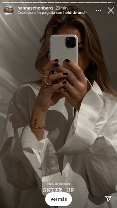 a woman taking a selfie with her cell phone in front of her face while wearing a white shirt