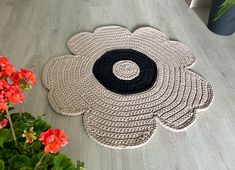 a black and white rug on the floor next to red flowers