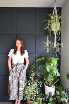 a woman standing in front of some houseplants and potted plants with her hands on her hips