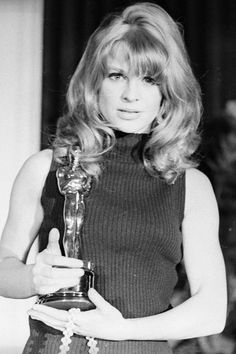 an old black and white photo of a woman holding an oscar award in her hands