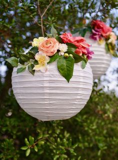 two white paper lanterns with flowers hanging from them