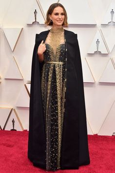 the oscars red carpet is dressed in black and gold, with an embellished cape