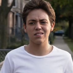 a young man is frowning in front of a house