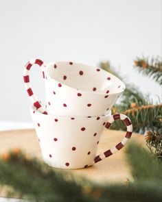 two white cups sitting on top of a wooden table