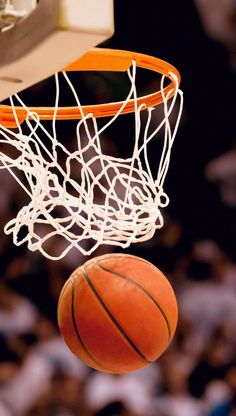 a basketball is going through the net to dunk it in front of an audience