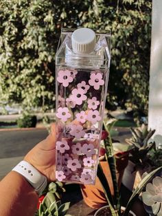 a hand holding a water bottle filled with pink flowers