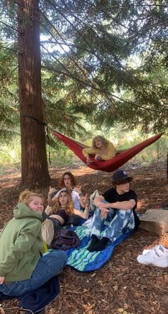 four people sitting in a hammock on the ground