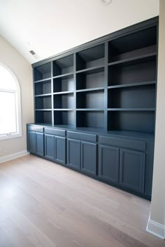 an empty room with blue bookcases and wood floors