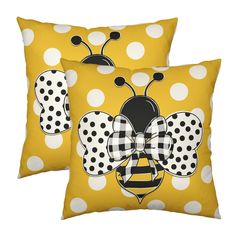 two yellow and white polka dot pillows with a bee on the front, one in black and