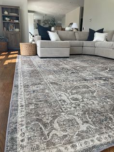 a living room area with a large rug on the floor and furniture in the background