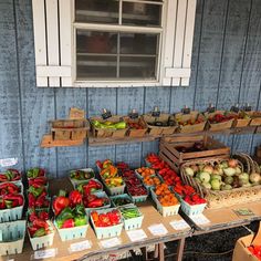 an outdoor farmers market with lots of fresh fruits and vegetables on the table in front of it