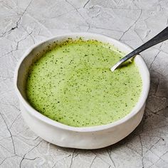 a white bowl filled with green soup and a spoon