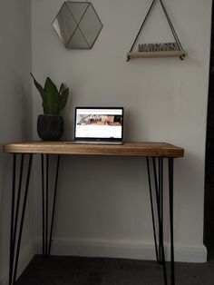 a laptop computer sitting on top of a wooden table next to a potted plant