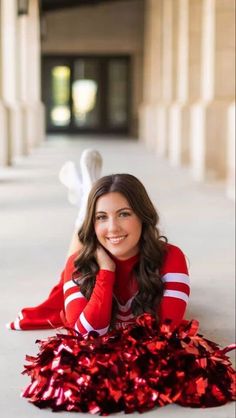 a woman laying on the ground wearing a cheerleader uniform and posing for a photo