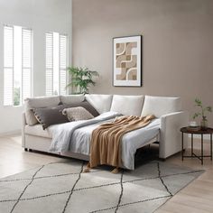 a white couch sitting on top of a wooden floor in a living room next to a window