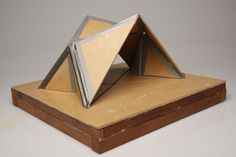 a small model of a pyramid on top of a wooden box with two pieces of cardboard