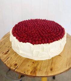 a cake with white frosting and raspberries on top sitting on a wooden table