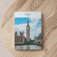 a book sitting on top of a wooden table next to a bridge and clock tower