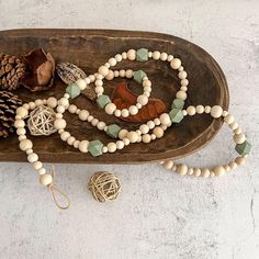 a wooden tray with beads and pine cones on the top, along with other items