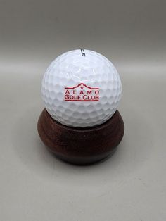 a white golf ball sitting on top of a wooden stand in front of a gray background