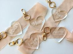 four clear heart shaped key chains with personalized names on them, hanging from satin ribbon