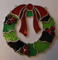 a stained glass christmas wreath ornament hanging on a wall