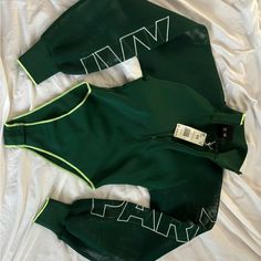 two green and white tracksuits laying on top of a bed next to each other