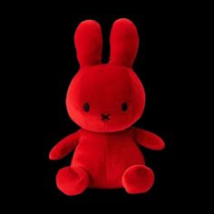 a red stuffed rabbit sitting in the dark