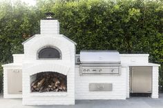 an outdoor pizza oven with firewood stacked in it's center and two doors open