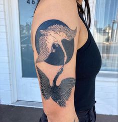 a woman with a black and white tattoo on her arm holding a bird in the middle