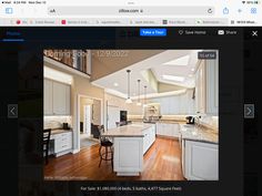 an image of a kitchen with white cabinets and wood floors on the web page for real estate listing