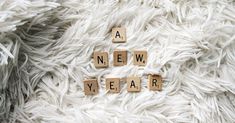 scrabble tiles spell out the word a new year on a white fuzzy surface