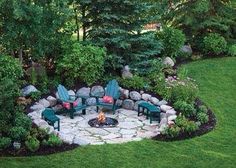 a fire pit surrounded by green chairs in a garden with rocks and grass around it