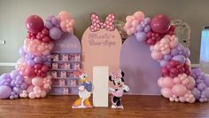 minnie mouse balloon arch and mickey mouse figurine in front of the entrance sign