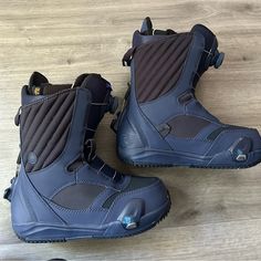 two snowboard boots sitting on top of a wooden floor