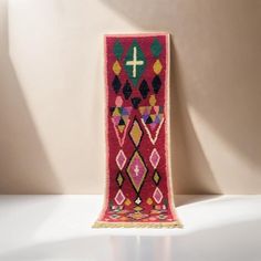 a colorful rug with a cross on the top is shown in front of a white wall