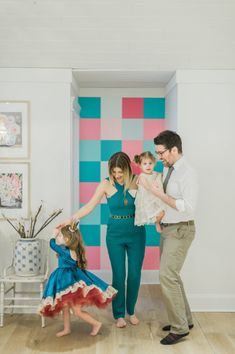 a family standing in front of a colorful wall