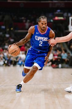 a basketball player dribbles the ball while being guarded by another player