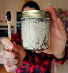 a person holding a jar with something in it and a toothbrush sticking out of it