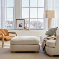 a living room with two chairs and a footstool in front of a window