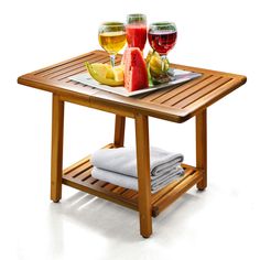 a wooden table topped with glasses of wine and fruit