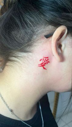 a woman with a red tattoo on her neck and behind her ear is a chinese symbol