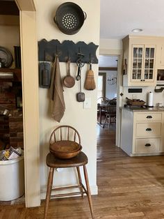 a wooden chair sitting in front of a wall mounted pot rack