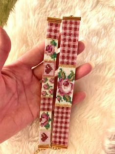 two pieces of pink and white beaded bracelets in the shape of flowers on red checkered fabric