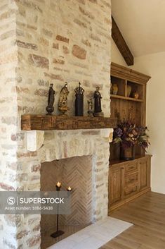 a stone fireplace in a living room next to a book shelf with candles on it