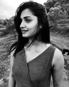 a black and white photo of a woman with long hair standing on a dirt road