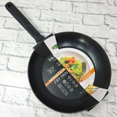 a black frying pan sitting on top of a white brick wall next to a knife and fork