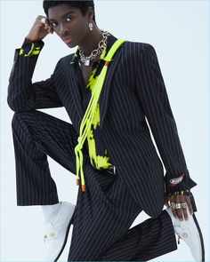 a woman in a suit and yellow scarf posing for the camera with her hand on her head