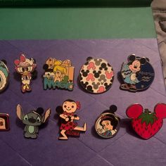 various disney pins and magnets sitting on a purple surface